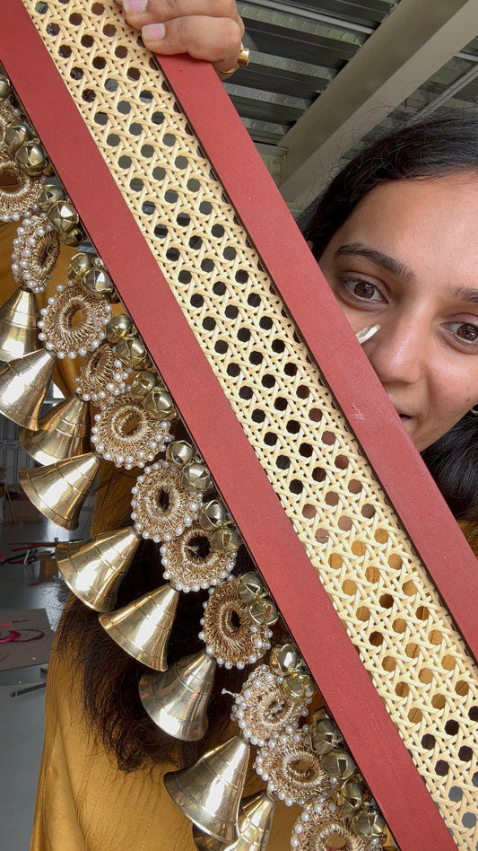 IBHI Navya Shobhā Toran with brass bells, rattan, crochet, and handpainted red panel – modern handcrafted décor