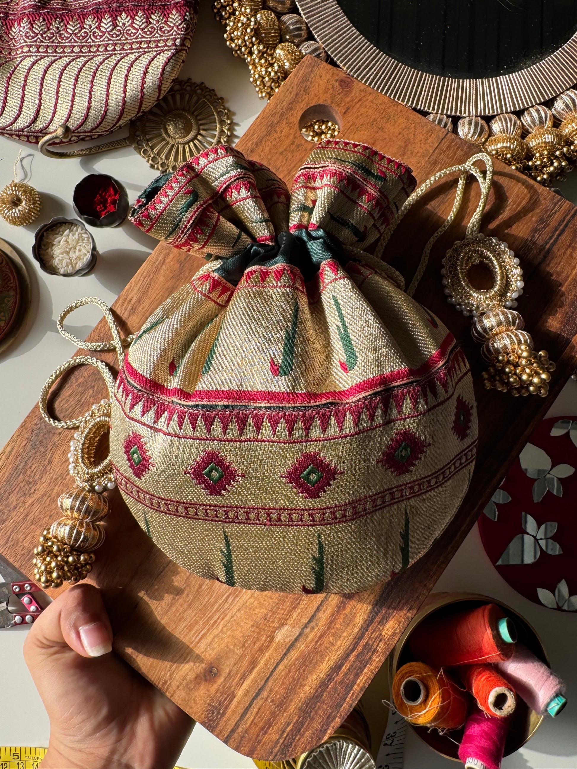 Maroon Paithani potli bag with golden zari weave and drawstring – ideal for wedding favors and festive return gifting. Named Shahi Kumkum by IBHI.