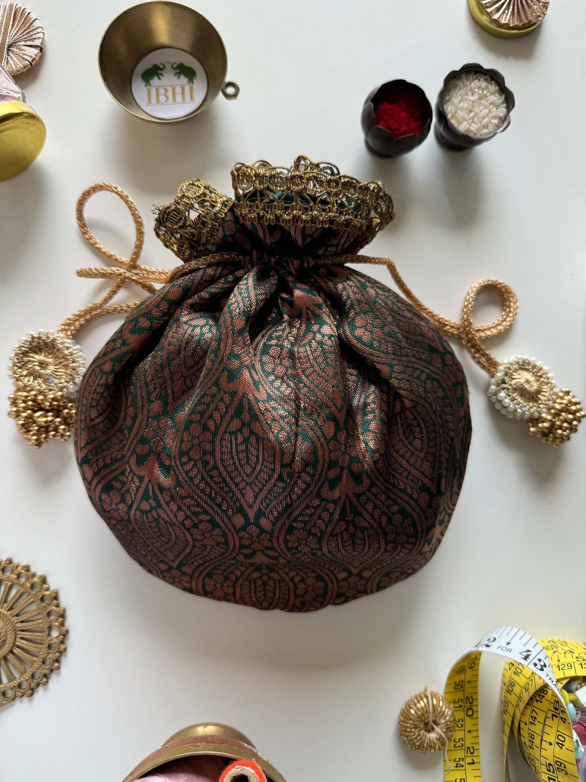 Handmade deep green potli bag made from upcycled saree with matte copper zari and crochet lace border – ideal for wedding favors and eco-friendly gifting