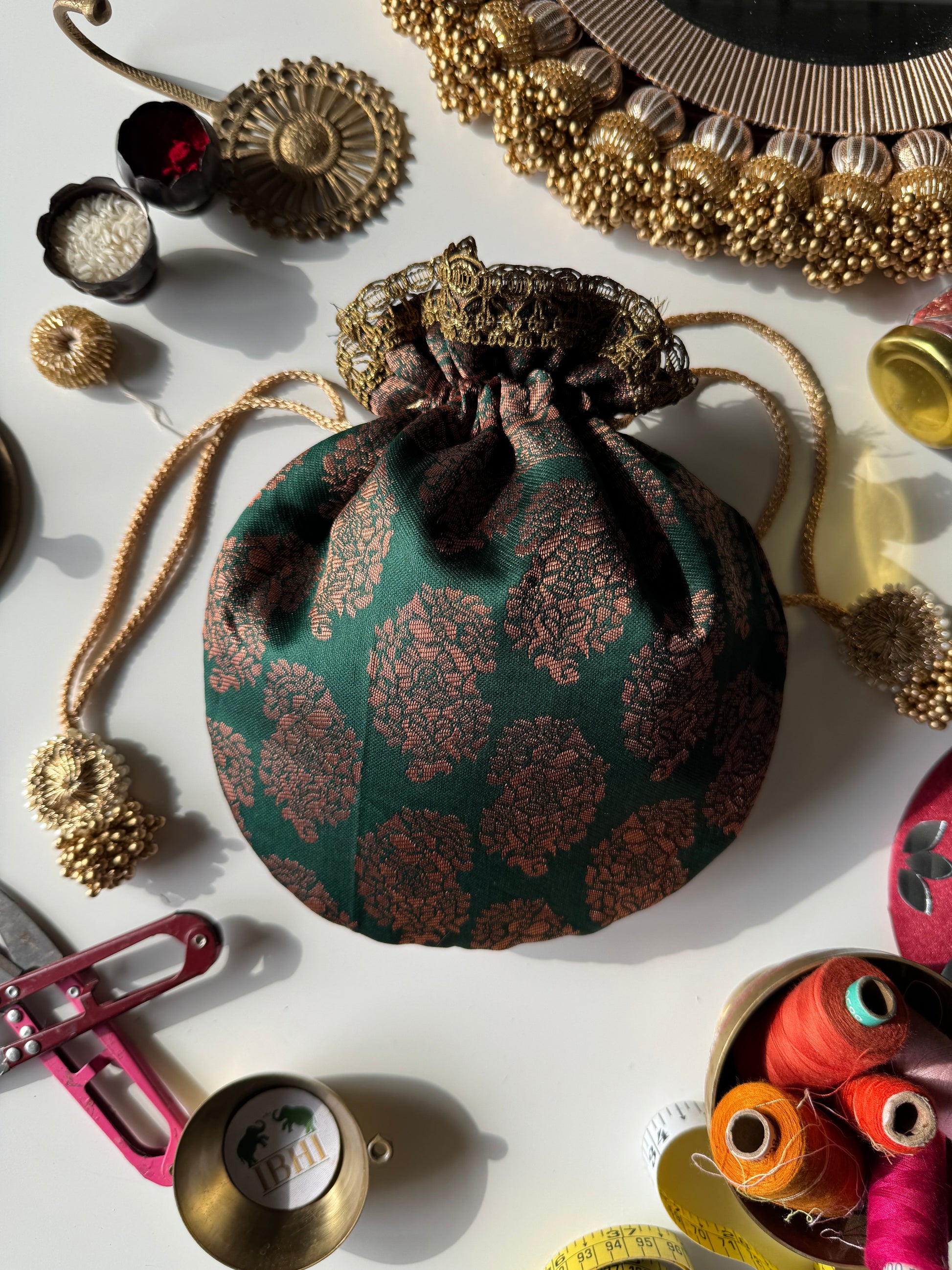 AmbiRaag potli bag featuring all-over paisley motifs in traditional design, padded and handmade – perfect for weddings and festive gifting.