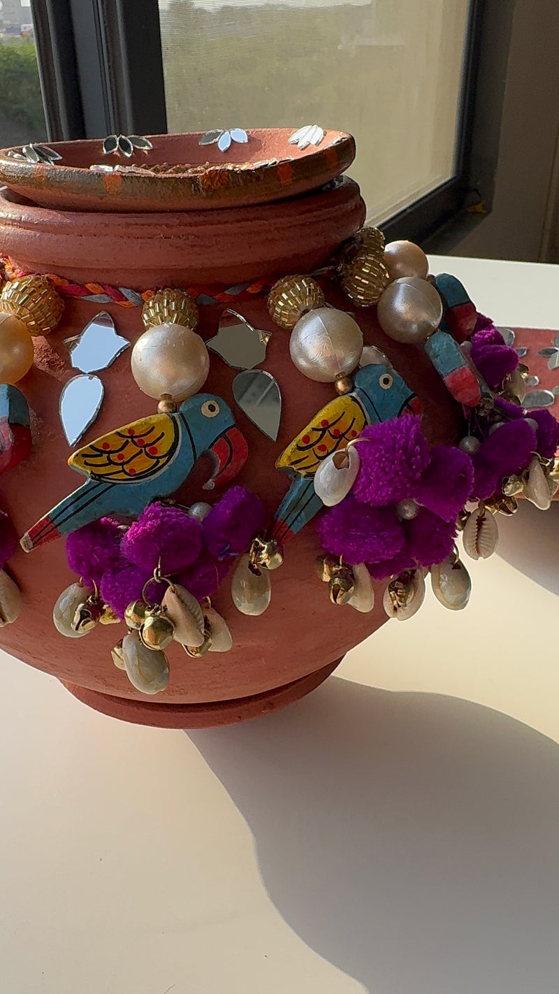 Ganesh puja matli with geru finish and parrot tassels by IBHI, handcrafted with mirror and pom-pom details, includes decorated kodiya.

