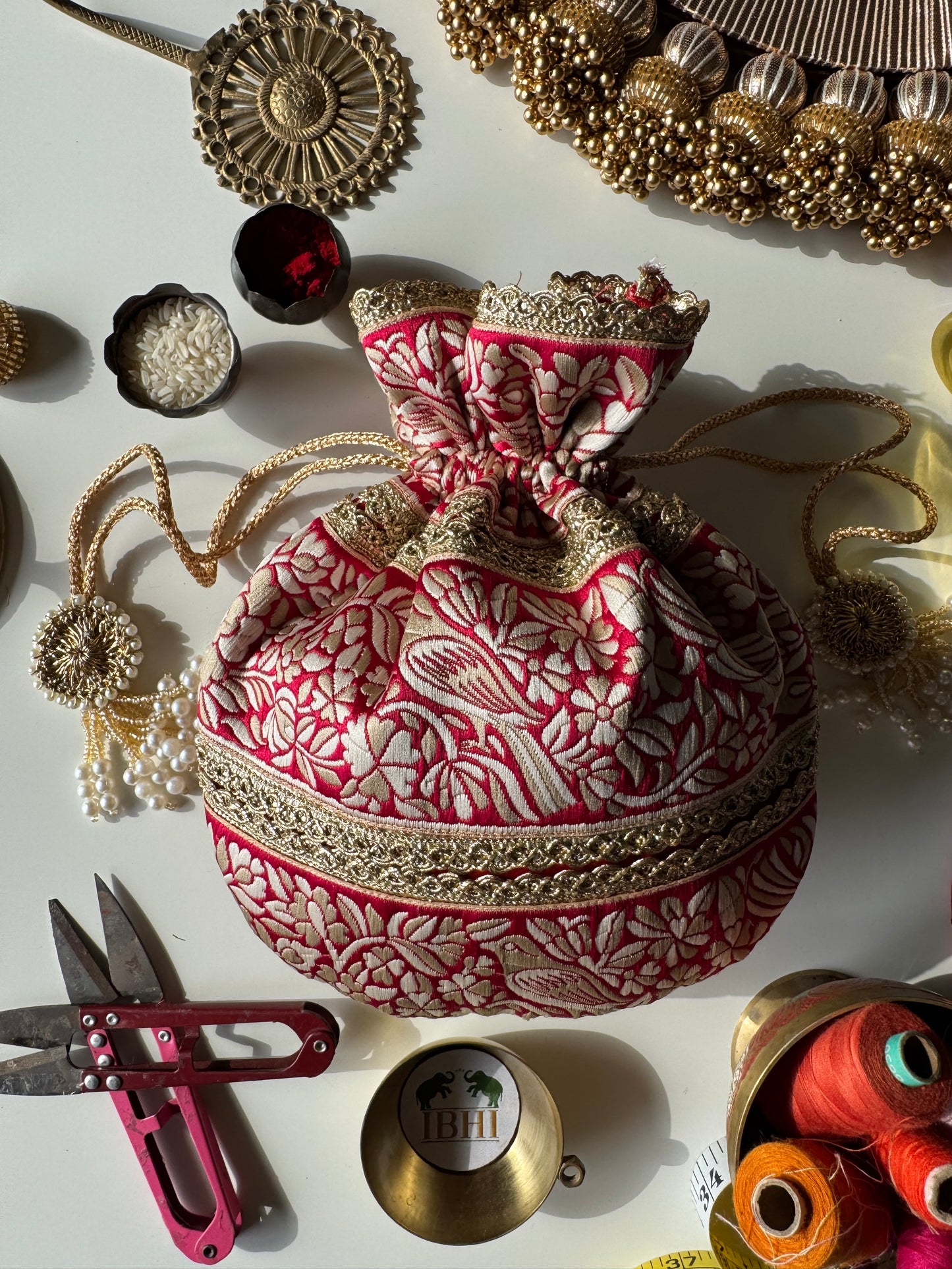 PakshiRaag potli bag featuring Parsi Gara bird embroidery on rich fabric with gold border and tassels – ideal for weddings and festive return gifts.

