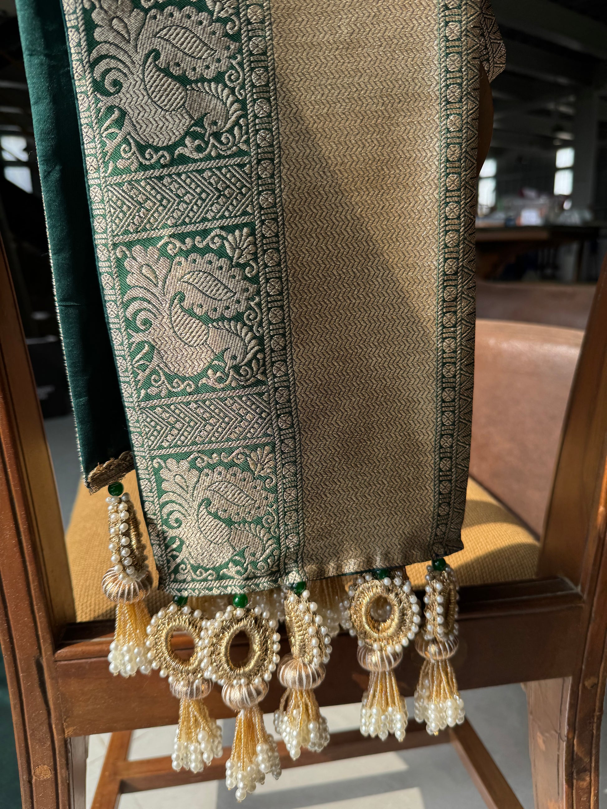 Sunehri Mayuri khes in deep emerald green with gold chevron zari weave, and handcrafted crochet, gota patti, and pearl tassels – IBHI


