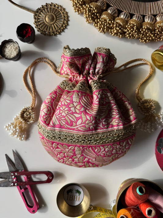 Pink and pastel green Parsi Gara potli bag with delicate floral embroidery, gold lace trim, and beaded tassels – ideal for gifting and wedding favors.

