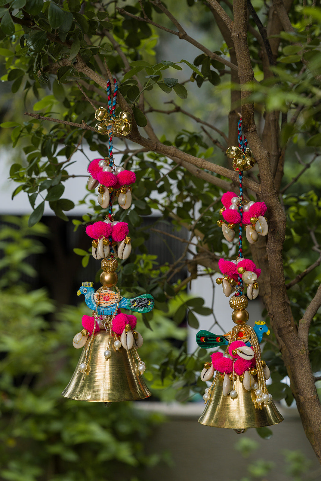 Handcrafted Indian peacock bell hanging with cowrie shells, pink pom-poms, beads and antique gold bell by IBHI